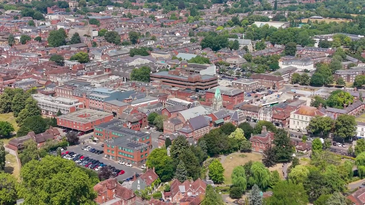 Drone si allontana dal centro di Winchester, rivelando tetti fitti, guglie di chiese e strade di questa storica città inglese