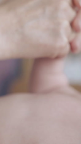newborn baby in white diaper lies on special table and enjoys professional hypertonus arms massage extreme close view