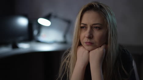 Pensive-woman-with-dirty-hair-sits-in-semi-dark-office