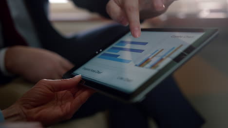 Hands-using-tablet-diagram-closeup.-Unknown-business-couple-working-on-flight