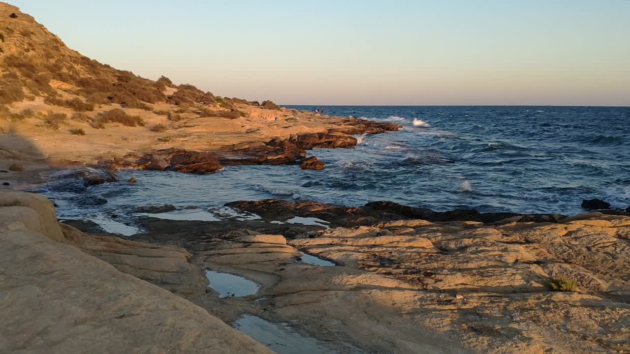 Golden hour coastal view at Cabo de Huertas, Alicante, with rocks and ocean waves