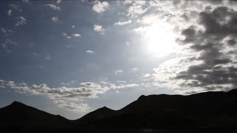 當太陽穿過天空時,雲端在中午的陽光下滾動在山脈上面的時間流