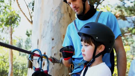 Man-assisting-child-to-fix-carabiner-on-zip-line-4K-4k