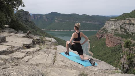 Mujeres-En-Forma-Estirando-Ambas-Piernas-Junto-A-Un-Lago