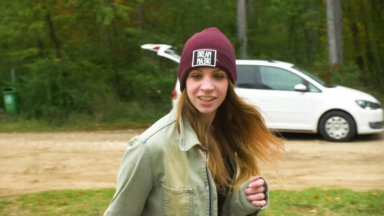 Happy Young girl with red hair in inline skates on the street, is skating backwards. Road in the forest during the autumn day.