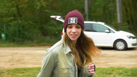 happy young girl with red hair in inline skates on the street, is skating backwards. road in the forest during the autumn day.