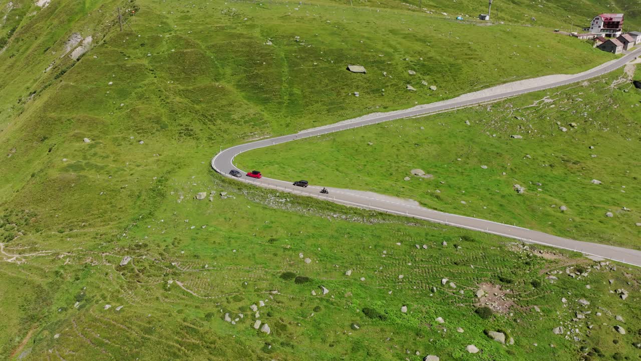 Drone view Swiss Alps winding mountain road with vehicles driving through nature