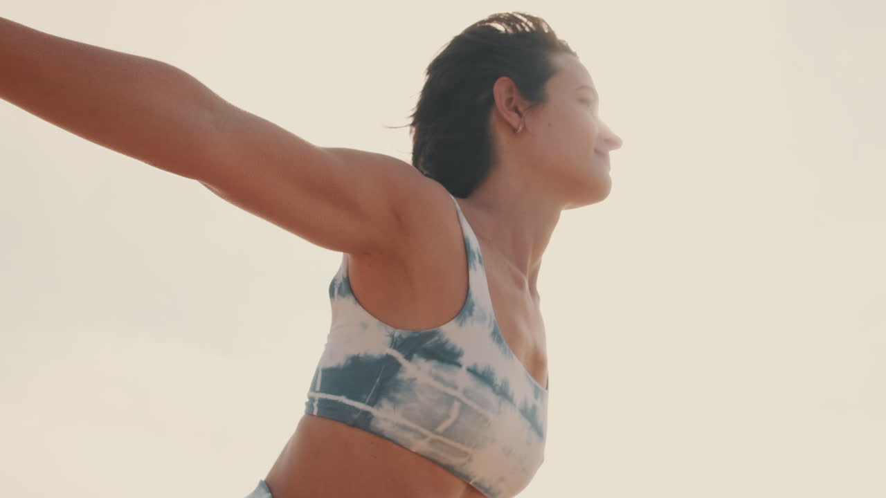 Serene Woman Stretching Arms Out in Yoga Pose Against Bright Sky
