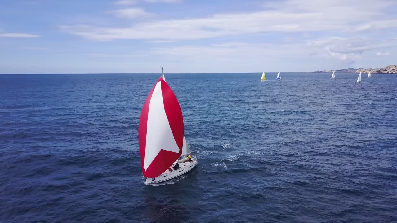Sailboat with red sails sailing on the Blue Sea during Regatta Race arround Kornati Islands in Croatia - Aerial Drone View