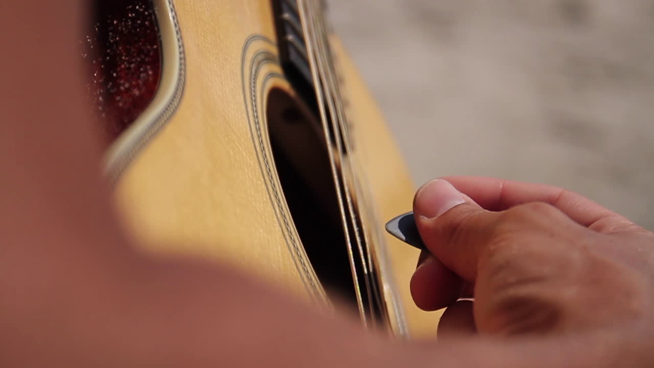 el hombre toca la guitarra en la playa
