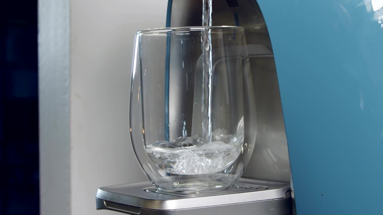 Gros plan au ralenti d'un verre d'eau se remplissant dans une machine de filtration d'eau