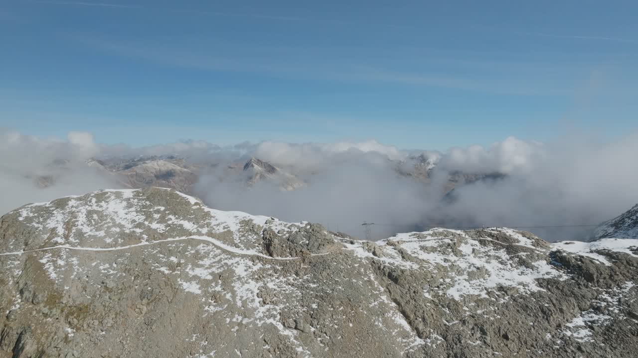 Soaring past rocky ridge revealing vast alpine mountain range, drone