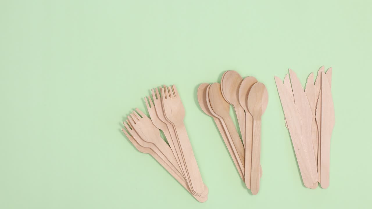 Group of Eco friendly zero waste, spoon, knife and forks appear on right side of light green background. Stop motion flat lay