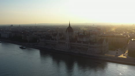 revealing drone shot into the sun, of the hungarian parliament building in budapest hungary