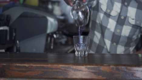 beautiful motion shot of professional barista making cocktail with two glasses at the bar. bartender burning sambuca.