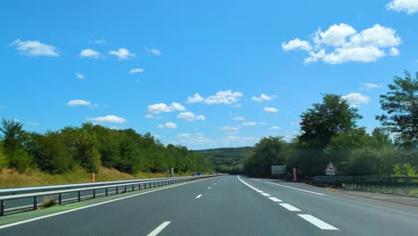 pov dashcam view travelling along french highway motorway freeway with cars passing with blue sky background with trees flying by quickly 4k