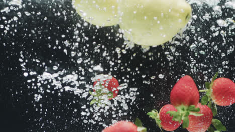 video of apples and strawberries falling into water with copy space on black background