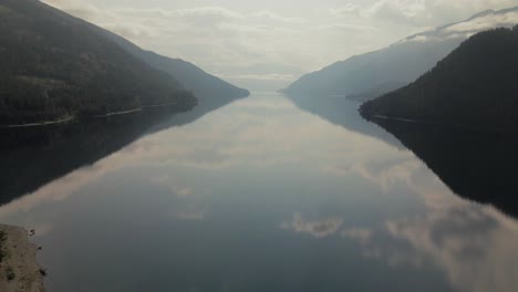 closing shot over the shoreline of slocan lake with a stunning reflection