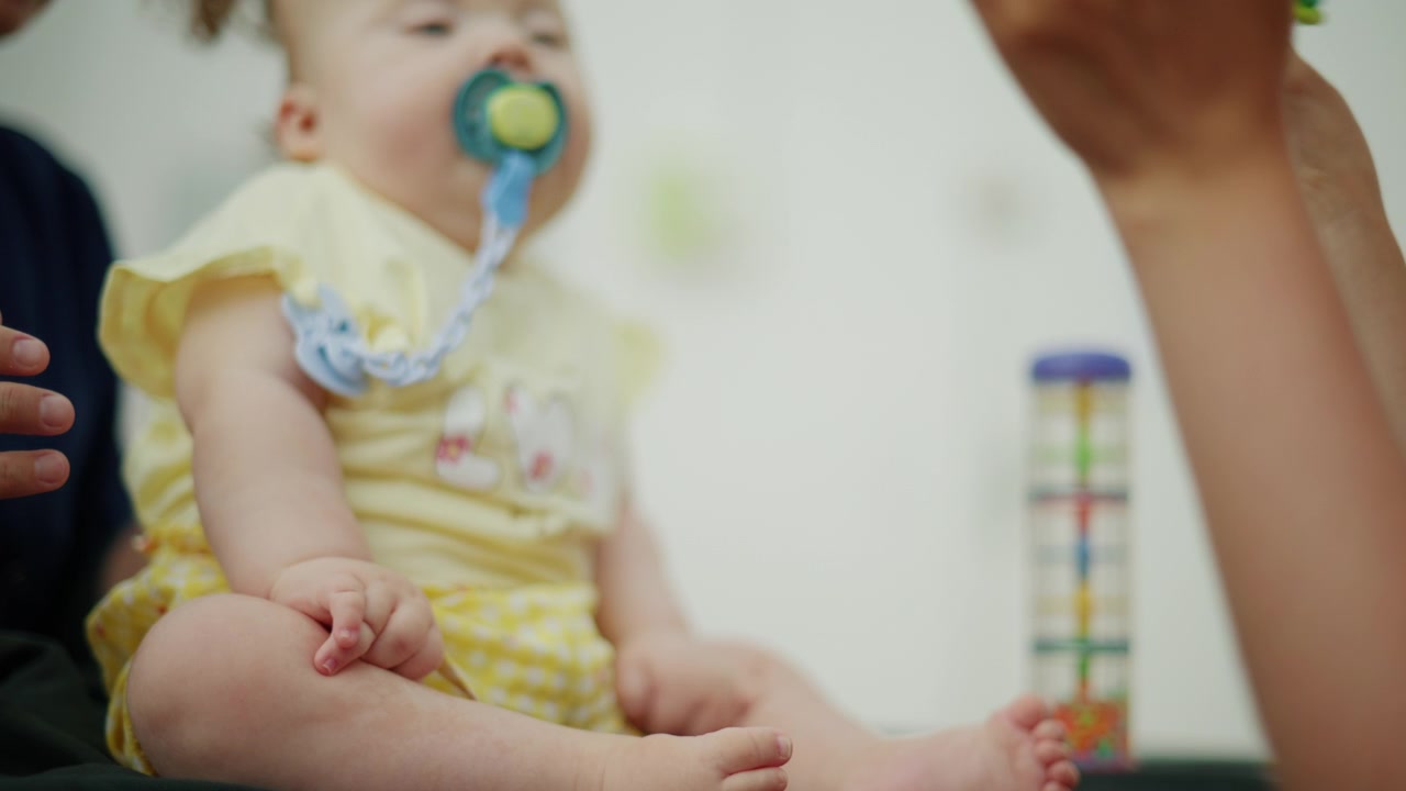 Genitore che tiene in braccio un bambino con vestiti gialli e un ciuccio, offrendo cure tenere e conforto. Concetto di sviluppo infantile