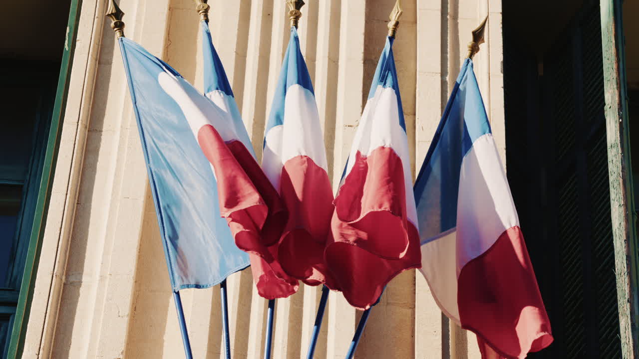 French national flags waving on the facade of a historic building in southern France