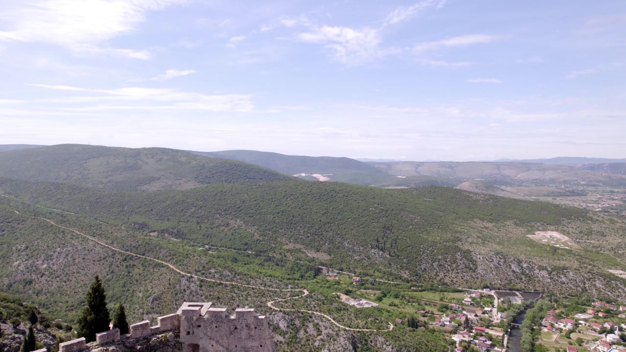 La Fortezza di Blagaj domina ampie valli montane e colline in Bosnia ed Erzegovina, sorvolo aereo dalle rovine verso creste distanti
