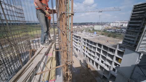 a worker uses steel tying wire to fasten steel rods to reinforcement bars. reinforced concrete structures - knitting of a metal reinforcing cage.