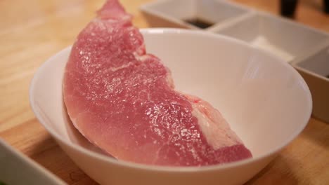 hand slide white bowl of pork loin in, close up