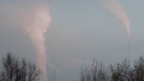 cooling tower and smokestack release smoke or steam in the background