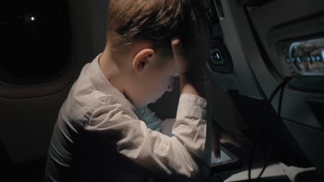 boy traveling by plane and playing chess game on digital tablet