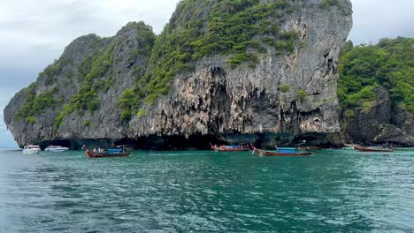 a captivating scene near phi phi island, thailand: a majestic rock adorned with lush greenery, framed by turquoise waters where four long-tail boats gracefully navigate