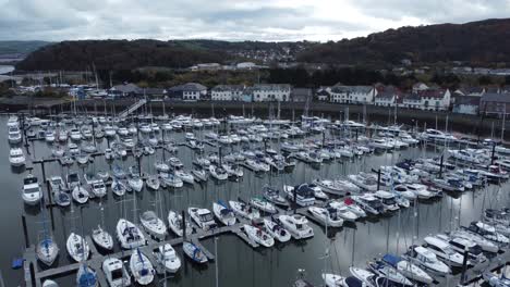 Scenic-luxurious-waterfront-harbour-apartment-village-yachts-and-sailboats-under-mountain-coastline-aerial-rising-over-view