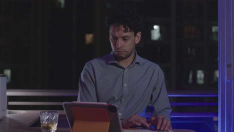 Concept-close-up-of-businessman-working-late-at-night-with-glass-of-brandy-on-desk