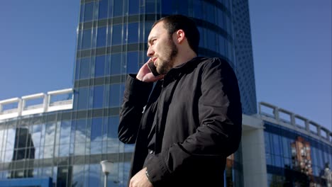 hombre hablando por teléfono y mirando su reloj al aire libre