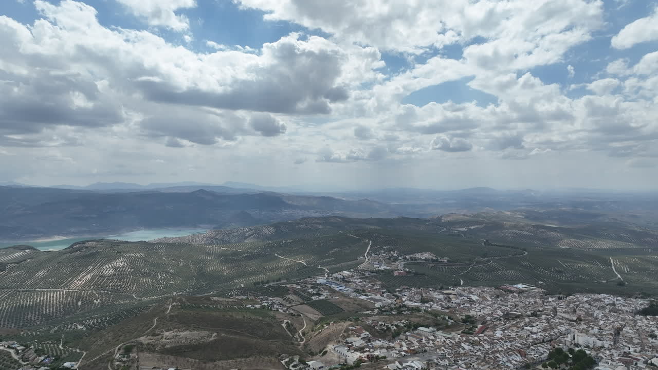 Aerial glides over Andalusian town of Rute over olive orchards to Lake Iznajar