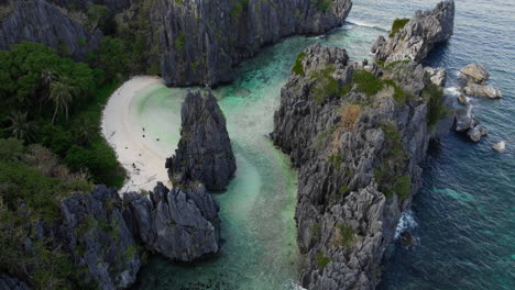 isolated tropical beach with white sand hidden by steep cliffs in philippines