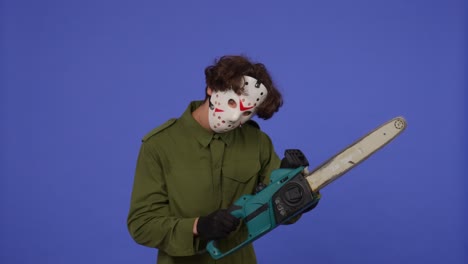 man in white mask with chainsaw in hands on blue background image of maniac jason voorhees from - man in white mask with chainsaw in hands on blue background. image of maniac jason voorhees from friday 13. halloween celebration concept