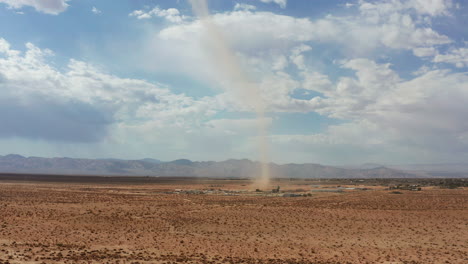 Una-Tormenta-De-Arena-O-Un-Diablo-De-Polvo-Con-Viento-Giratorio-Envían-Una-Nube-De-Polvo-En-El-Cielo-Como-Un-Pequeño-Tornado---Vista-Aérea-Hacia-Atrás