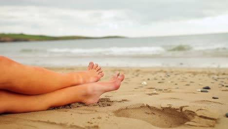 Frauenbeine-Sitzen-Am-Strand