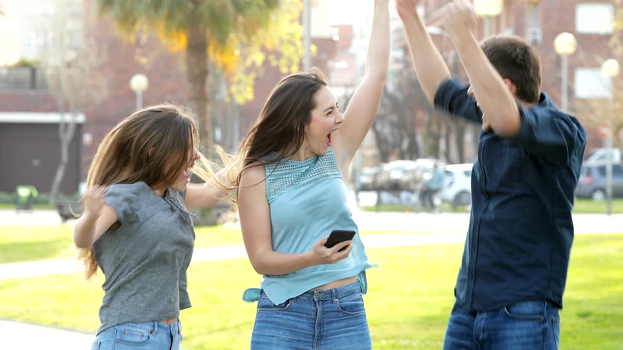 Excited friends jumping after checking phone content