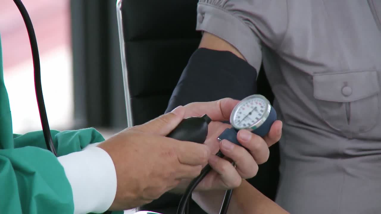 의사 는 사람 의 혈압 을 확인 하고 있다