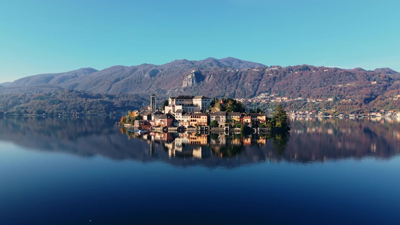 Vista aerea: Isola di San Giulio, Basilica di San Giulio e Lago d'Orta di giorno in Piemonte, Italia nord-occidentale, ripresa con drone in orbita