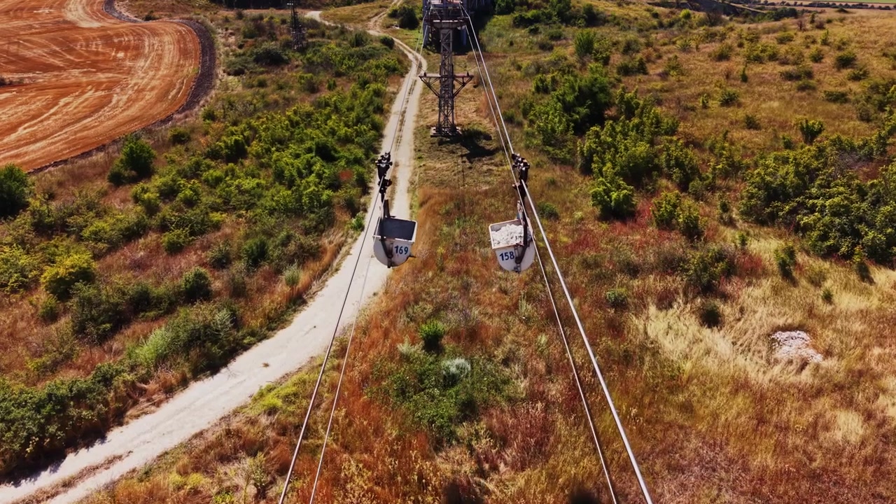 Sistema de cabos transportando rochas através de um campo em uma área rural