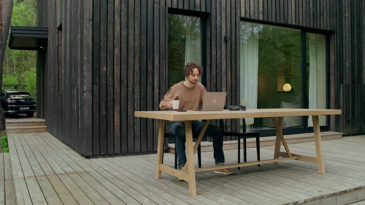 hombre trabajando en una computadora portátil en un patio de madera