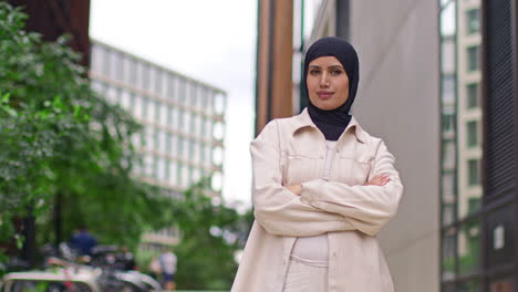 porträt einer modernen muslimischen geschäftsfrau mit hijab und geschäftsanzug, die mit gefalteten armen vor einem bürogebäude steht und zur arbeit geht 3