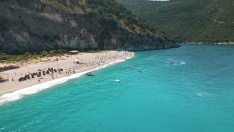 low aerial overview of tourists strolling on beautiful sandy beach of the albanian riviera