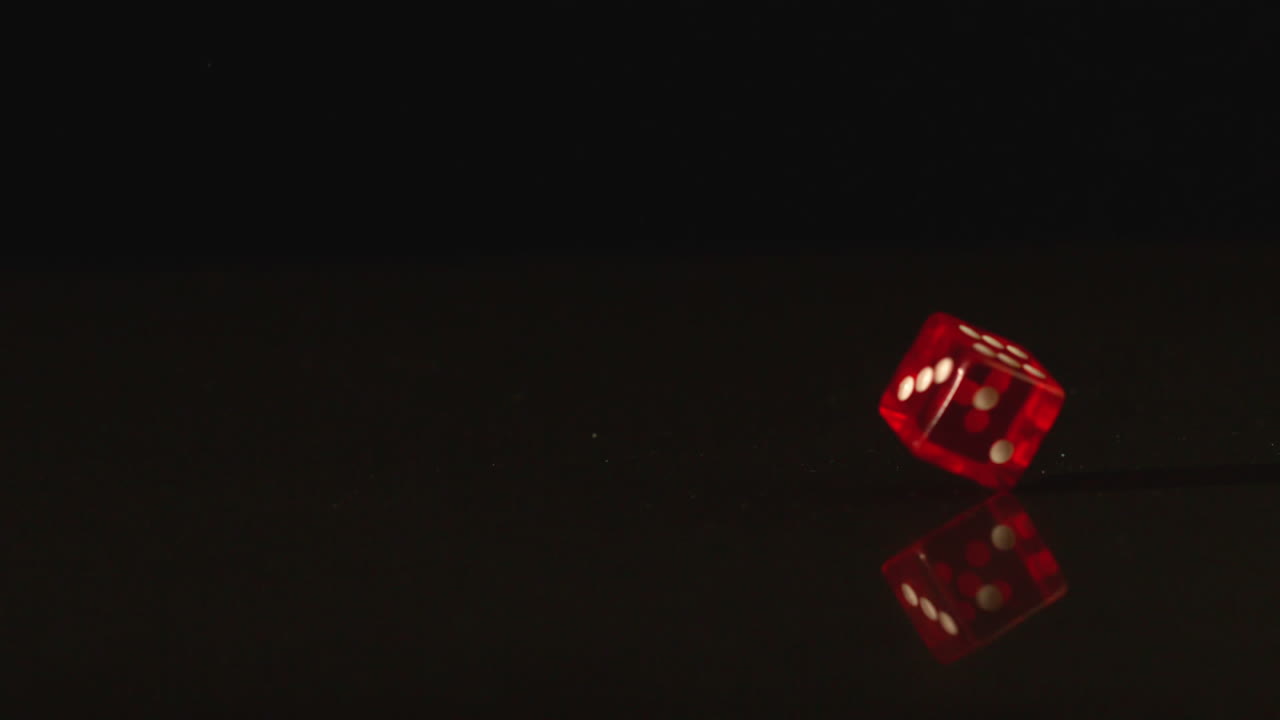 Red plastic dice spinning on black background