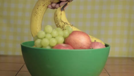 hand picking fruit from from a choice of fruit in a bowl medium shot