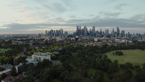 Paisaje-Urbano-De-Melbourne-Con-Hermoso-Cielo-Colorido-Que-Revela-El-Parque-Debajo,-Tiro-Aéreo