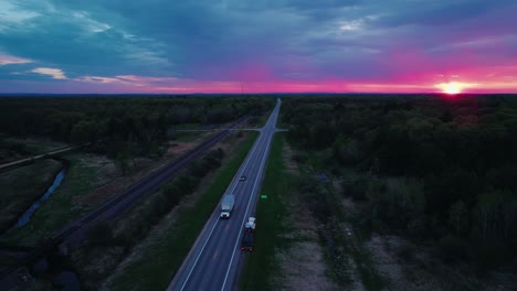 sunset drone aerial of semi-truck on forest-lined highway in wisconsin
