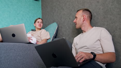 caucasian parents work on laptops sitting at home. couple with newborn child using laptops. low angle view.